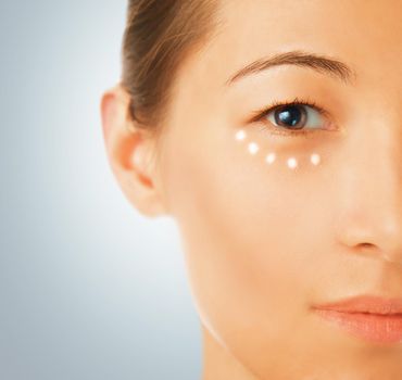 Portrait of a beautiful young woman, a cream applied around the eye, concept of skincare