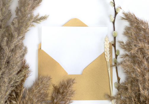 Minimalistic card mockup with reed flower, craft envelope, blossom, flat lay, top view Blank white paper card and envelope for copy space space for text