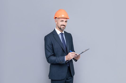 engineer man in businesslike suit and hardhat making notes, signing contract.