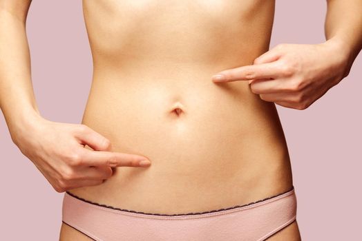 Unrecognizable woman points to the abdomen, circle arrows on the stomach, concept of comfortable digestive system