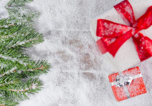 Gifts and Christmas tree branch in the snow, top view