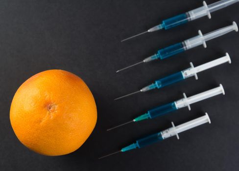 Blue liquid in the syringe and grapefruit, top view
