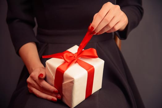 Unrecognizable woman in dress is opening a present, front view