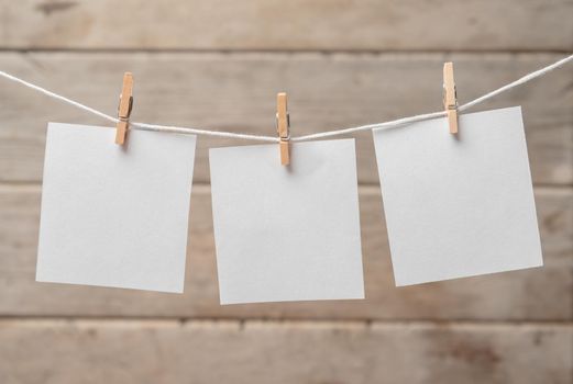 Sheets of paper on a clothespins on a wooden background, space for text