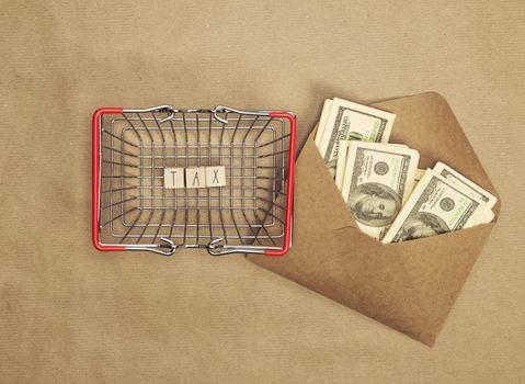 Personal tax income concept, cube wooden block with word TAX with envelope with dollars, business and financial concept copy space top view craft paper