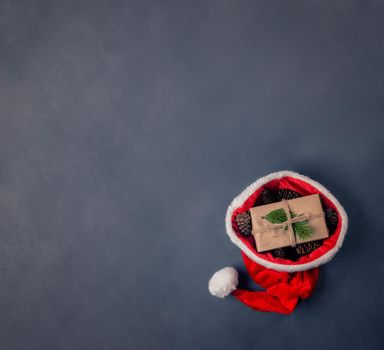 Present in eco wrapping with cones in santa hat, space for text