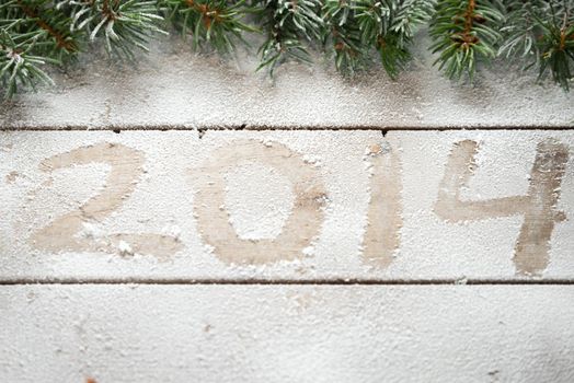 Branches of Christmas tree above the inscription 2014 in the snow