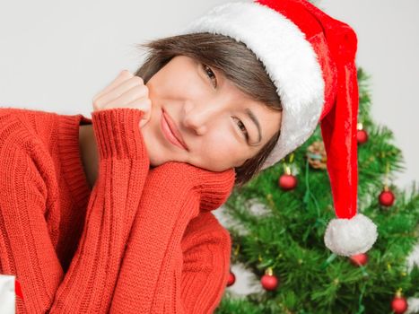 Beautiful woman in a santa hat smiling on the background of Christmas tree