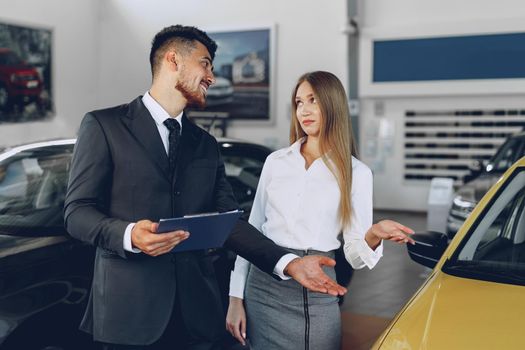 Man car dealer showing a woman buyer a new car. High quality photo