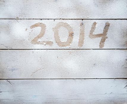 2014 written in snow on a wooden table