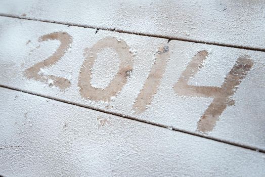 2014 written in snow on a wooden background