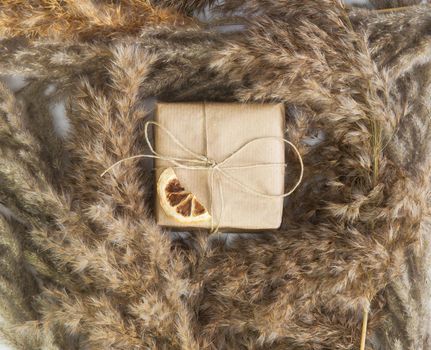 Gift box wrapped in craft paper top view surrounded with dried pampass grass, modern background, Mothers Day, Birthday, Greeting card concept vintage