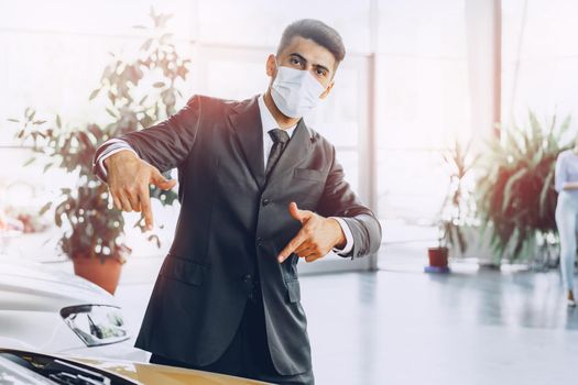 Man car dealer wearing protective medical mask on his working place, coronavirus prevention concept