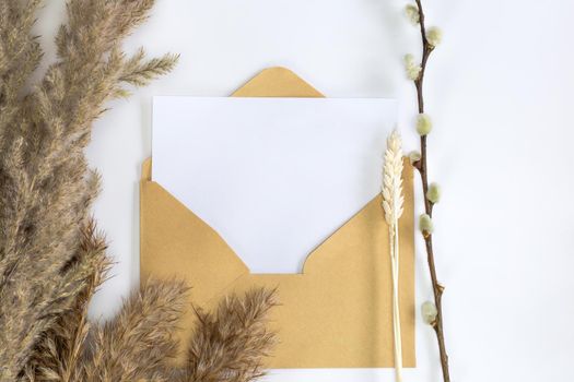 Minimalistic card mockup with reed flower, craft envelope, blossom, flat lay, top view Blank white paper card and envelope for copy space space for text