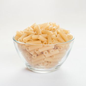 Straight macaroni in a transparent bowl, side view