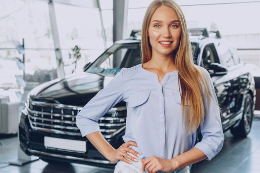 Young woman checking out a new car she is going to buy in car salon