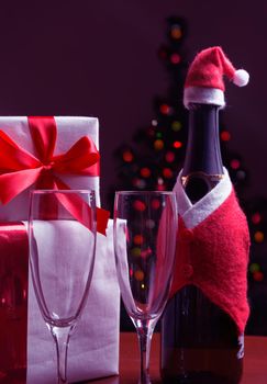 Bottle of champagne, glasses, gift boxes on the background of Christmas tree