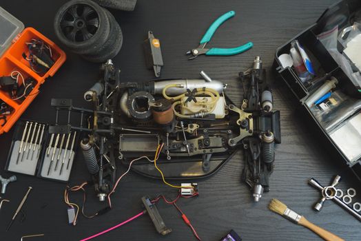 Young Caucasian male assembling toy RC car at home in the evening.