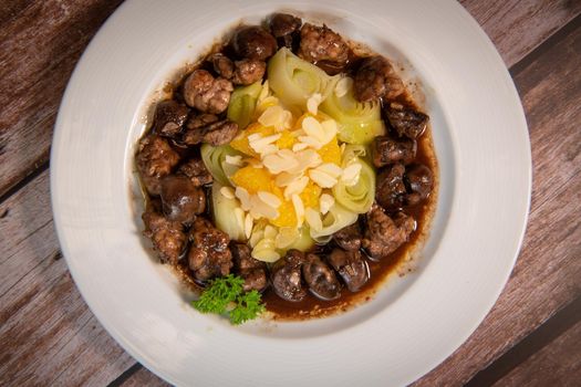 Recipe of sweetbread and lamb kidney with cocoa, leek whistles with almonds and oranges. High quality photo