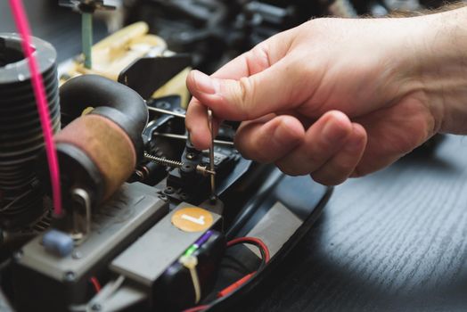 Young Caucasian male assembling toy RC car at home in the evening.