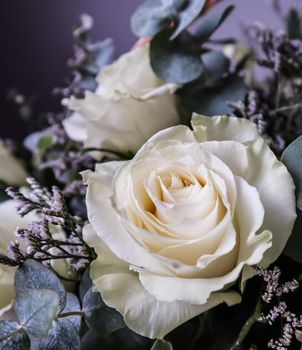 Bouquet of beautiful white roses in a wicker basket on a dark background. Perfect for greeting card