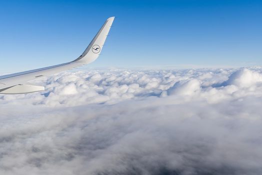 22.05.2021 Frankfurt, Germany - The Airbus A321 wing with Lufthansa airline logo and blue sky over clouds background. airplane wing in sunny day