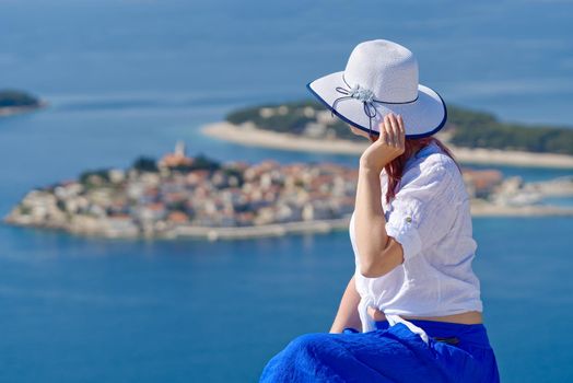 Beautiful tourist woman in a white straw hat on beautiful blue Adriatic Sea and cozy island background. Croatia during summer holiday. Luxury life at holiday at turquoise sea, ocean. Travel concept, Greece