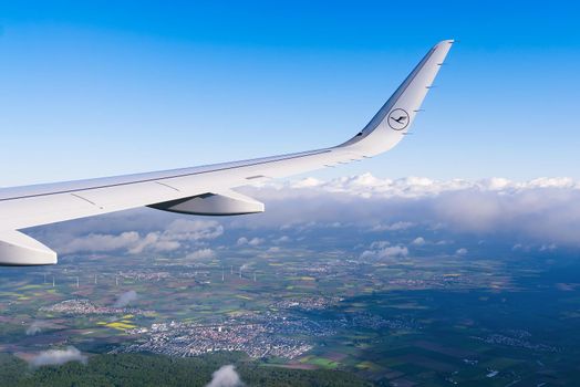 22.05.2021 Frankfurt, Germany - The Airbus A321 wing with Lufthansa airline logo and blue sky over clouds background. airplane wing on landing in frankfurt am main