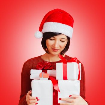 Happy young woman is holding many gifts on a red background