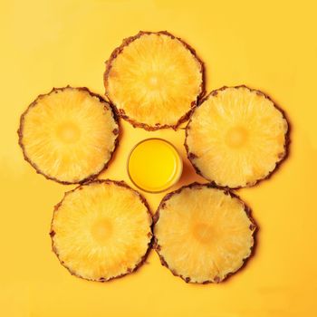 Pineapple juice and pineapple round pieces on a yellow background