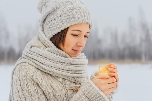 Young woman holds a candle in winter weather
