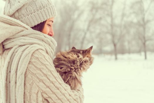 Young happy woman holds a cat in winter weather, concept of friendship