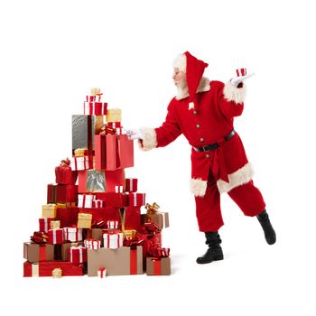 Santa Claus putting boxes into large pile of Christmas gifts isolated on white background