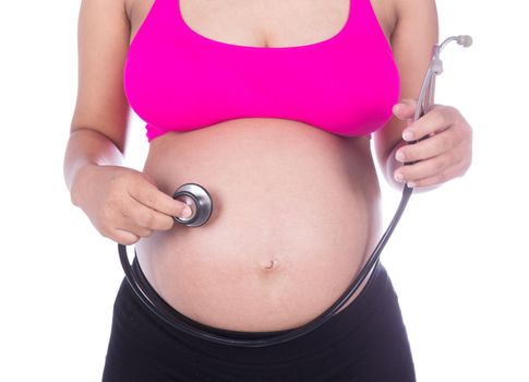 close-up of pregnant woman with stethoscope listening belly to baby