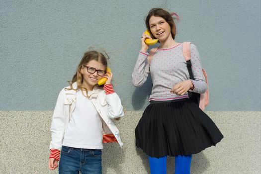 Girls teenager and child playing talking on abstract phone banana.