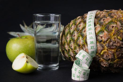 Fruits and glass of water with a measuring tape, concept of diet