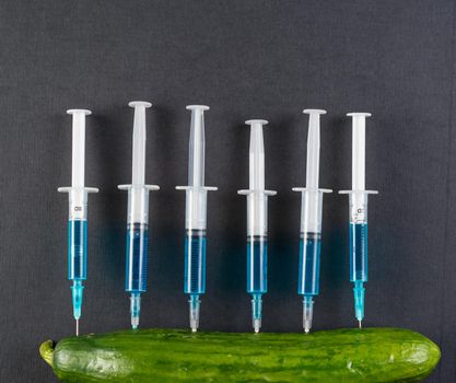 Blue liquid in the syringe injected into cucumber, space for text