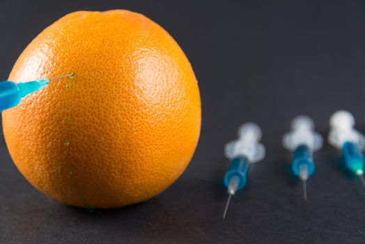 Blue liquid in the syringe injected into grapefruit, top view