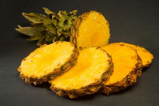Sliced ripe pineapple on a black background