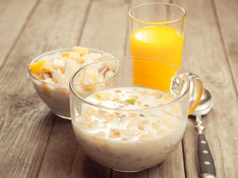Healthy breakfast on a wooden table: muesli with milk and fruit salad