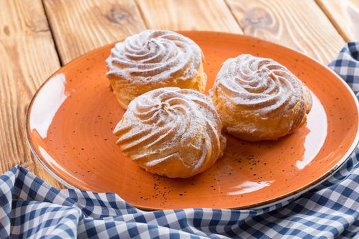 Small french cookies profitroles with sugar powder close up