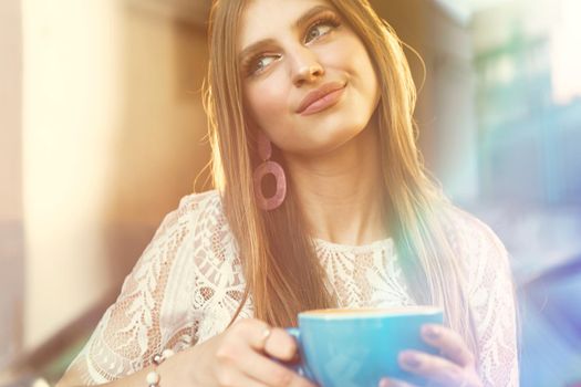 Portrait of a young woman having a cup of coffee and looking through the window. Close up.