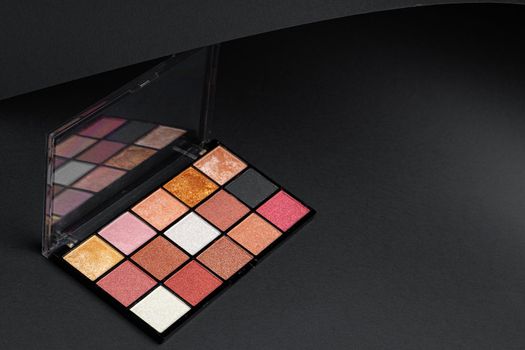 Color professional cosmetic palette on a dark background, close up