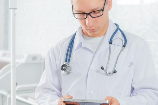 Man doctor works on a tablet computer in hospital
