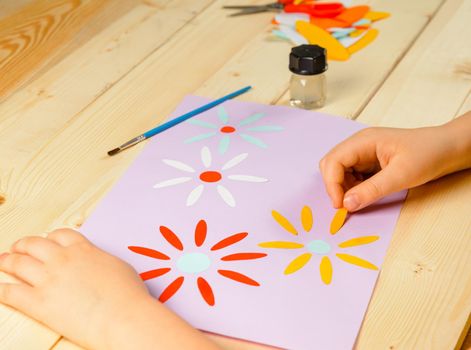 Child makes a greeting card for mother on holiday
