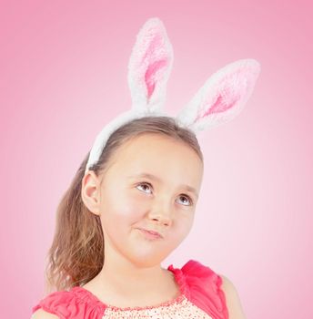 Portrait of little pensive girl dressed in Easter bunny ears on a pink background