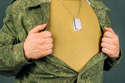 Military man opens his shirt, space for text, face is not visible