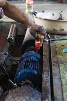 Hand of repairman oiling gear and during maintenance work of electric motor