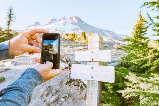Taking Mobile Photo of the Wooden Direction Sign on the Route to the Mt. Hood Top, Oregon, USA