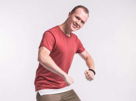 Attractive young man dancing, having fun on white background. Stylish outlook